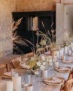 the table is set with place settings and flowers in vases, candles, and napkins