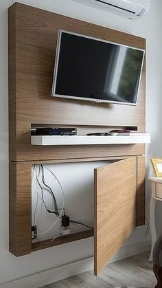 a flat screen tv mounted to the side of a wooden cabinet in a living room