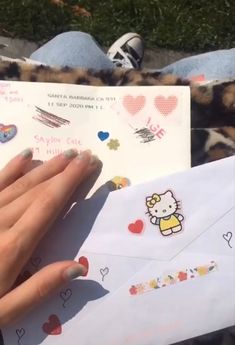 a person holding an envelope with hello kitty stickers on it