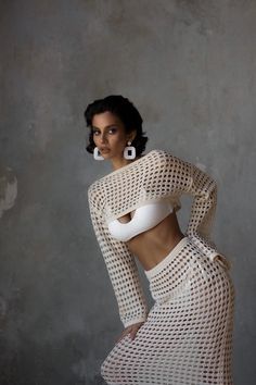 a woman in a white top and skirt posing with her hands on her hips while wearing large hoop earrings