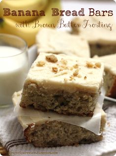 banana bread bars with brown butter frosting stacked on top of each other next to a glass of milk