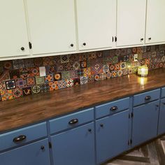 a wooden counter top in a kitchen with white cabinets and blue cupboards behind it