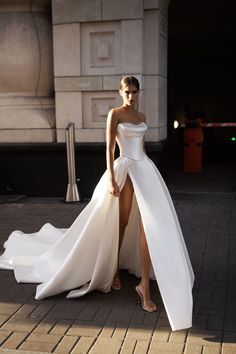 a woman in a white dress standing on the sidewalk