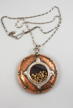 The Copper Seed Depository is a domed and planished copper vessel captured together with brass rivets. The central silver drum holds white peppercorns and capped with a glass lens. Rivets Jewelry, Riveted Jewelry, Etched Copper Jewelry, Copper Necklaces, Metal Clay Art, Copper Jewelry Diy, Rivet Jewelry, Kinetic Jewelry, Copper Ornaments