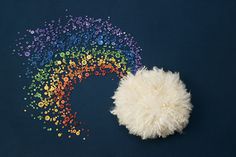 a white fluffy ball sitting on top of a blue floor next to a rainbow wall