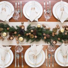 the table is set with pine cones and white plates