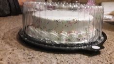 a cake with white frosting and sprinkles sitting on top of a counter