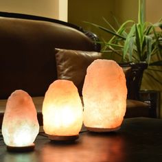 three himalayan salt lamps sitting on top of a table next to a brown leather couch