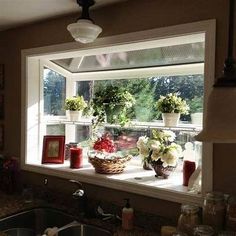 a kitchen window with flowers and candles on the windowsill, in front of a sink