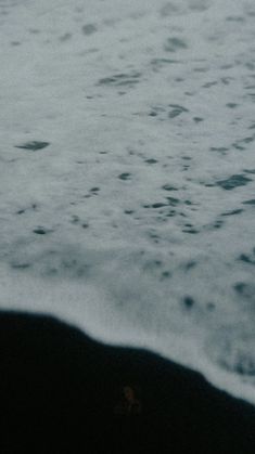 a surfer is walking into the ocean with his surfboard in hand and waves crashing on the shore