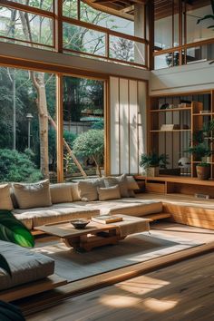 a living room filled with lots of furniture and large windows overlooking the trees in the background