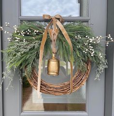 a wreath with a bell hanging on the front door