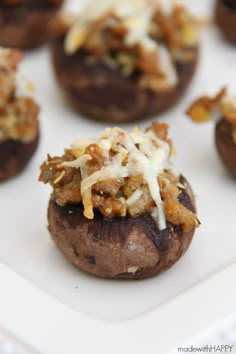 several stuffed mushrooms with cheese and sauce on top are sitting on a white platter