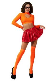 a woman in an orange top and red skirt posing for the camera with her hands on her hips