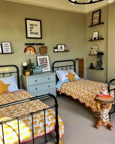 two twin beds in a bedroom with pictures on the wall above them and a small table next to it