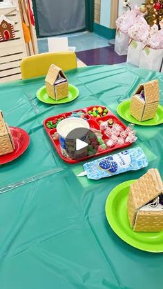 a table topped with green plates filled with cakes and desserts next to a christmas tree