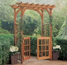 an outdoor wooden arbor with potted plants on the ground and trees in the background