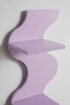 a purple shelf sitting on top of a white wall