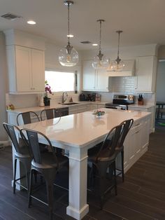 a large kitchen with an island in the middle and chairs at the counter top on the side