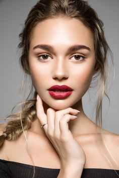 a woman with long hair and red lipstick posing for the camera, wearing a black off shoulder top