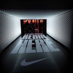 the nike logo is lit up in an empty room with white and black letters on it