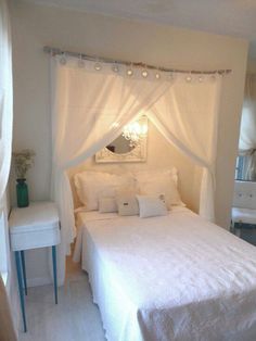 a white bed sitting under a window next to a night stand