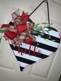 a heart shaped door hanger with the word hello written in red and black on it