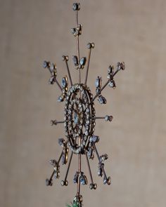 a metal and glass snowflake hanging from a ceiling in front of a wall