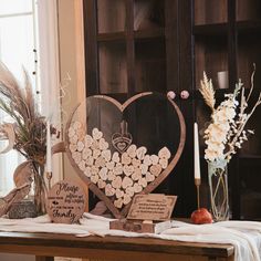 a heart shaped wooden sign sitting on top of a table next to a vase filled with flowers