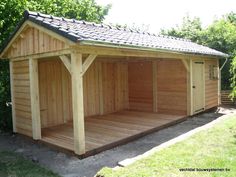 a large wooden shed with a black roof