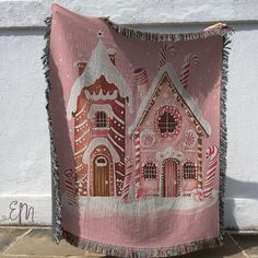 a pink blanket with houses on it hanging from the side of a white house wall