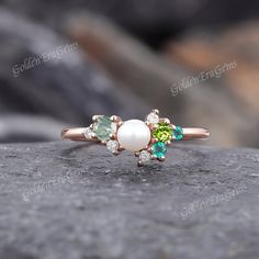 a close up of a ring with pearls and stones on it's side, sitting on a rock