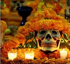 a skull with orange flowers and candles in front of it