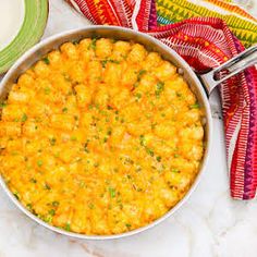 a casserole dish with cheese and parsley in it on a white table