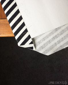 a black and white striped table cloth sitting on top of a wooden table next to a piece of wood