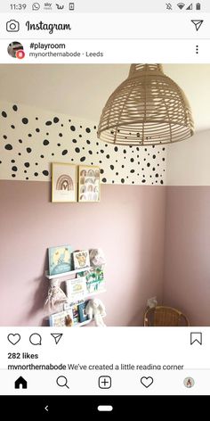 a room with pink walls and black polka dots on the wall, along with a wicker hanging light fixture