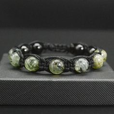 This gorgeous men's or women's bracelet is made of  10 mm AAA green Prehnite, 10 mm Black Tourmaline, black strong nylon cord, ending with 6 mm Black Tourmaline. Chakra - Solar plexus PREHNITE links our heart directly to our solar plexus chakra and assists us to live life from a heart-based perspective. Our heart knows what we truly want to do in this world, and how to find happiness. It will aid you to connect with angels and with spirit guides and was known in the past as a stone of magic. Prehnite will push individuals living passively towards a higher vibration and help one stay in tune with the energy within. The bracelet is packed in a WHITE COTTON GIFT BAG. A GIFT MESSAGE is available. MEASURE YOUR WRIST: 1. Please measure your wrist with a piece of string, tape, or similar, just be Black Round Bracelets With Sliding Knot, Green Stone Bracelet, Cotton Gift Bag, Black Tourmaline, Green Stone, Stone Bracelet, Plexus Products, Womens Bracelets, Arm Band