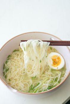 a bowl of noodles with an egg on top and chopsticks in the bowl