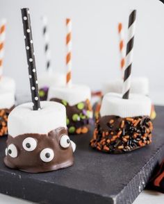 chocolate covered marshmallows with halloween decorations and candy sticks sticking out of them