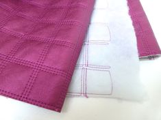 two pieces of cloth are laying on top of each other, one is pink and the other is white