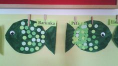 two paper plates with fish on them hanging from clothes pins in the shape of leaves