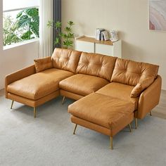 a tan leather sectional sofa with chaise lounge in an empty living room, next to a potted plant