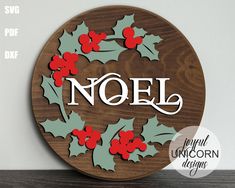 a wooden sign with holly leaves and the word noel on it