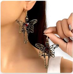 These stunning skeleton butterfly earrings add an edgy and unique touch to your look. Designed with intricate wings and a striking red heart, these statement pieces perfectly blend Gothic style and delicate craftsmanship. Ideal for anyone who loves to stand out, these earrings are the perfect accessory for festivals, parties, or adding a bold flair to your everyday wear. Make a lasting impression with these one-of-a-kind earrings! Luxury Handmade Jewelry For Halloween, Luxury Collectible Jewelry For Halloween, Heart Wings Earrings, Beaded Halloween, Cat Spider, Spider Pumpkin, Women Skeleton, Funny Jewelry, Halloween Clay