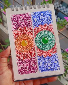 a hand holding a notebook with an intricate design on it