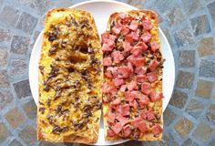 two pieces of bread with meat and cheese on them sitting on a plate next to each other