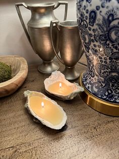 two oysters on a table next to some silver vases with candles in them