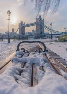 a bench covered in snow next to a bridge