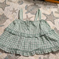 Nwt. Pale Green And White Plaid Multi Ruffled Top With Wide Straps On Shoulders. Has Accent Tie In Front Of Shirt. Very Cute. Cotton Ruffle Hem Top For Vacation, Cotton Tops With Ruffle Hem For Vacation, Cotton Top With Ruffle Hem For Vacation, Beach Cotton Top With Ruffle Hem, Cotton Beach Top With Ruffle Hem, Cute Brunch Tops With Ruffle Hem, Cute Ruffled Blouse For Vacation, Cute Ruffled Beach Blouse, Gingham Ruffle Tops For Vacation