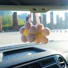 some crocheted balls hanging from a car dashboard